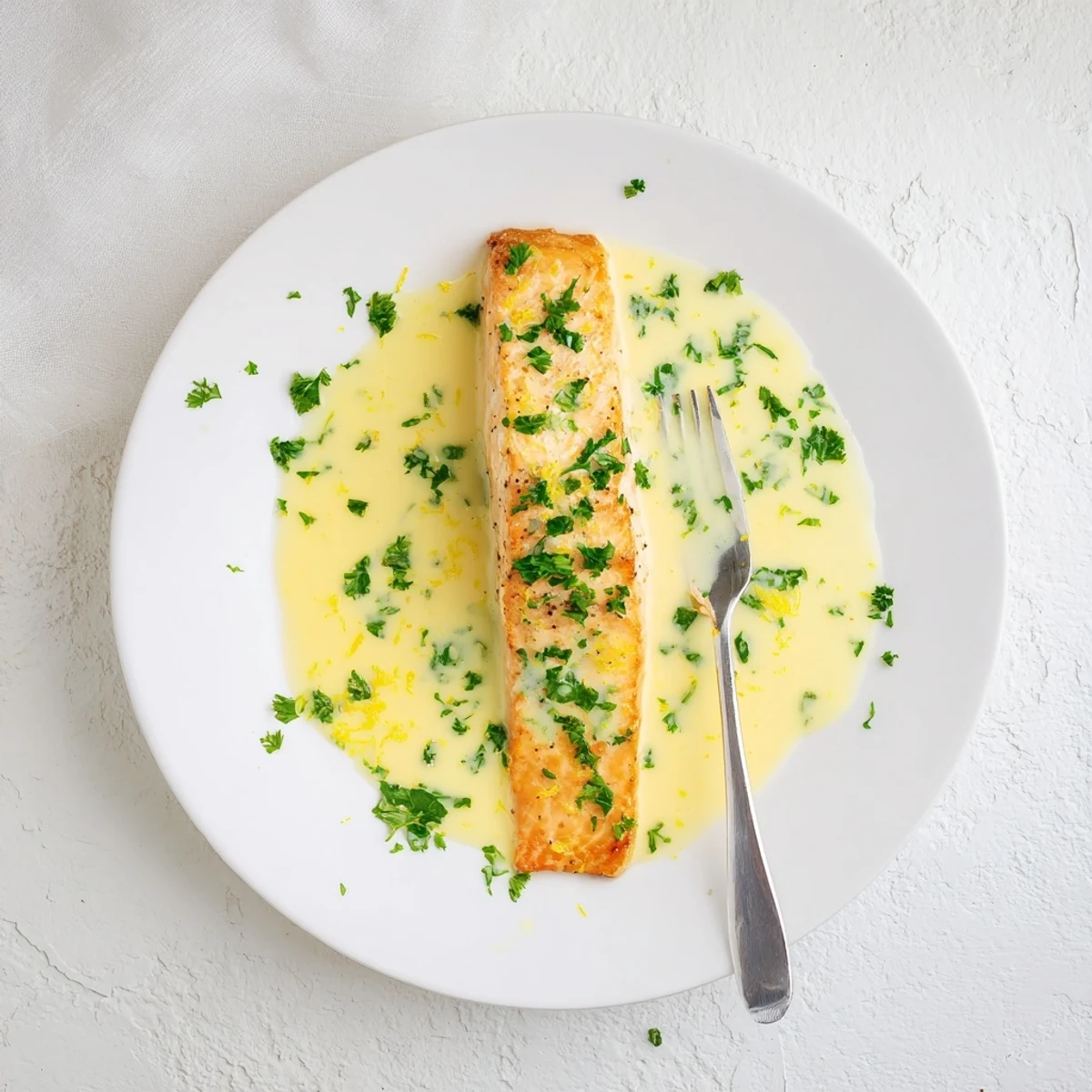 Golden brown salmon with lemon cream sauce drizzled over the crispy pan-seared fish