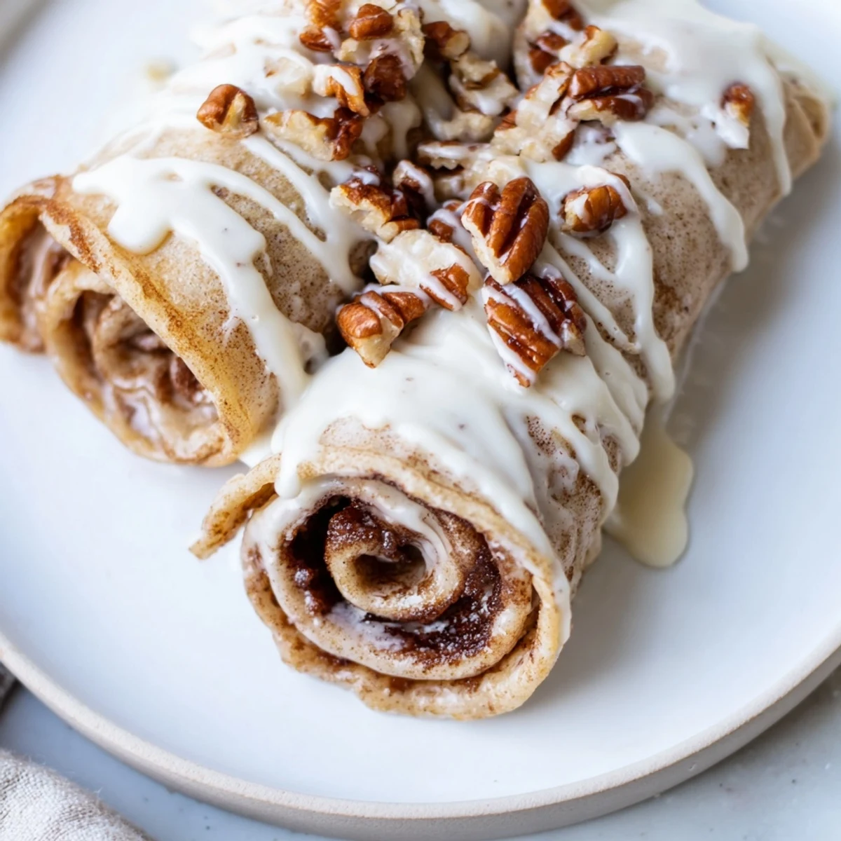 Stacked Cinnamon Roll Protein Crepes topped with powdered sugar glaze and fresh berries