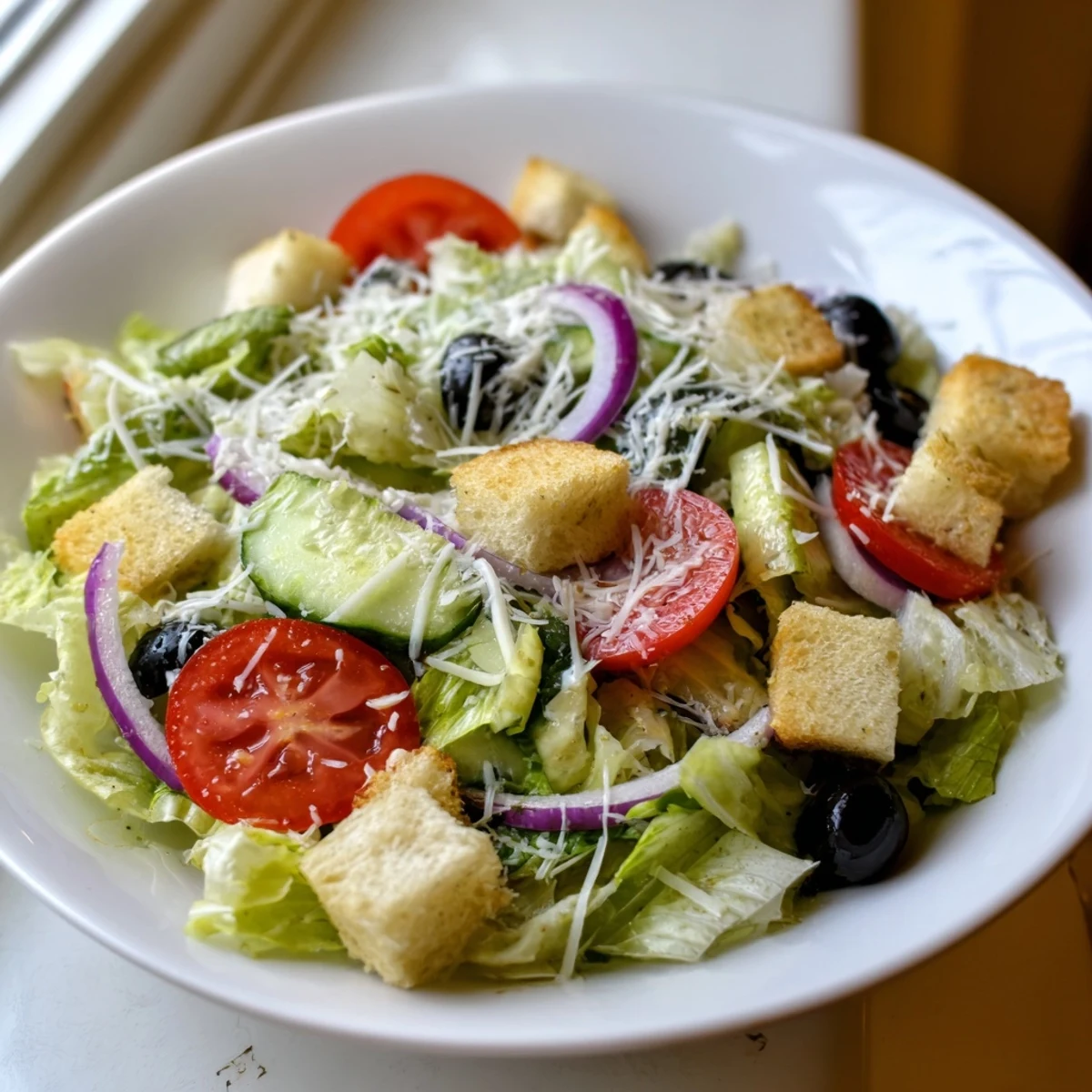 Fresh Olive Garden salad featuring romaine, tomatoes, pepperoncini, and black olives drizzled with vinaigrette.