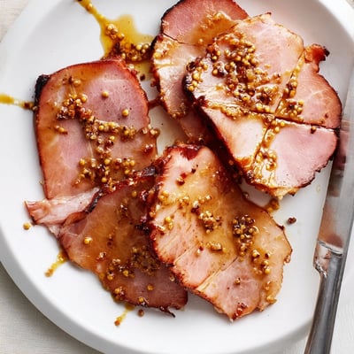 This Brown Sugar Mustard Glazed Ham rests on a wooden board, ready to be sliced for a festive family meal.