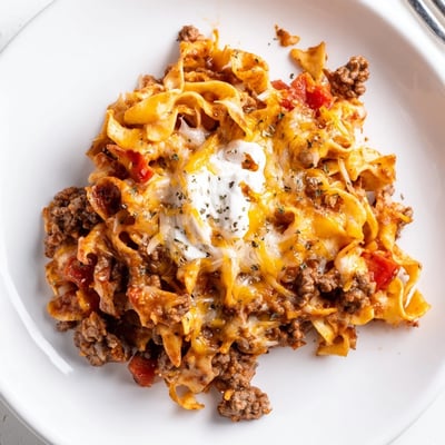 Creamy Beef Noodle Casserole steaming beside garlic bread and crisp green salad