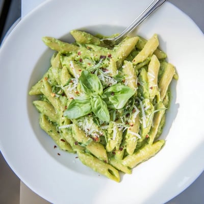 Vibrant green goddess pasta sauce served over penne with fresh basil garnish